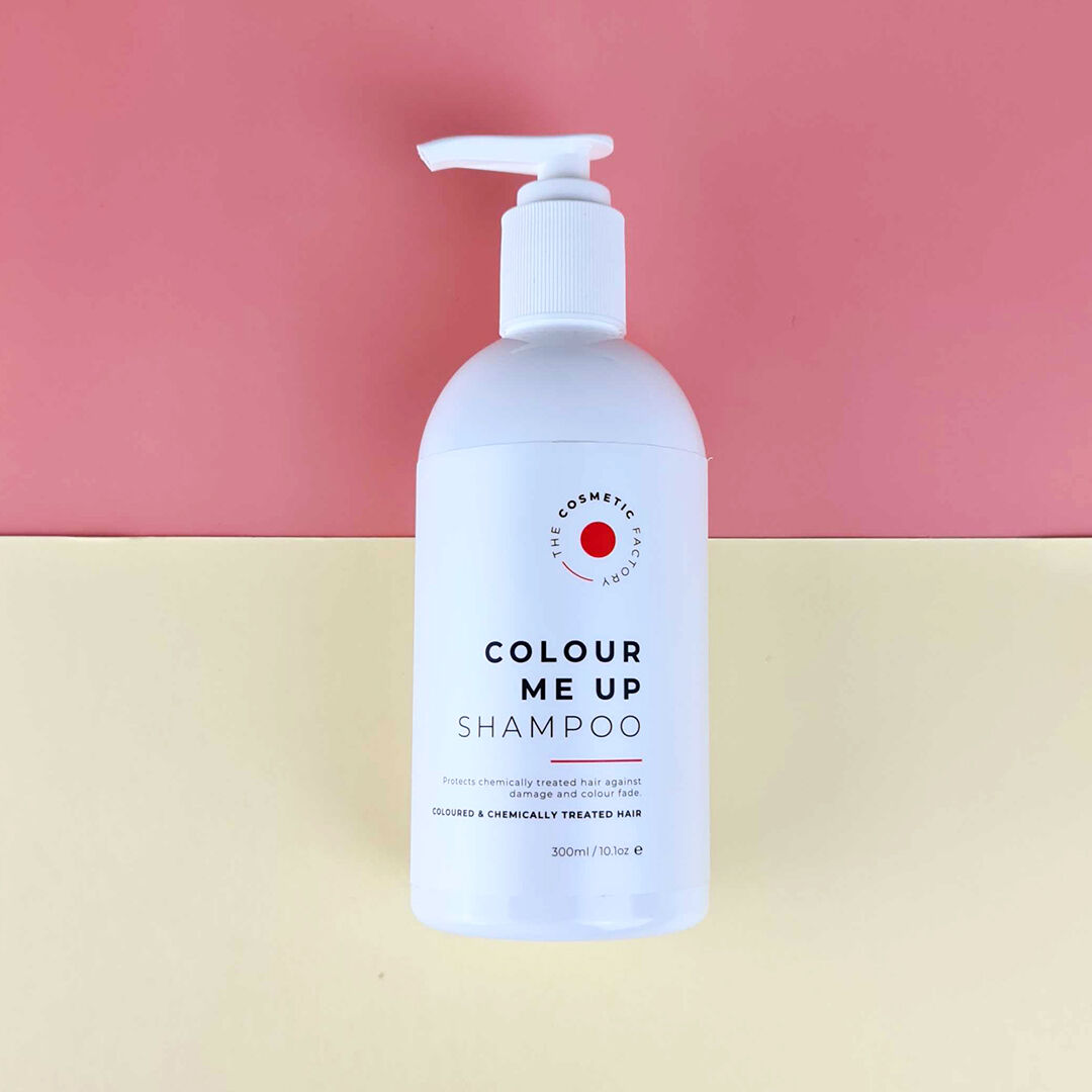 a bottle of colour me up shampoo 300ml on a red surface.