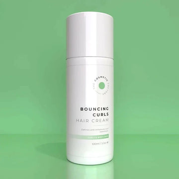 a bottle of bouncing curls hair cream 100ml on a green surface.