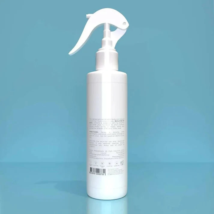 a bottle of build me up spray 225ml against a blue background.