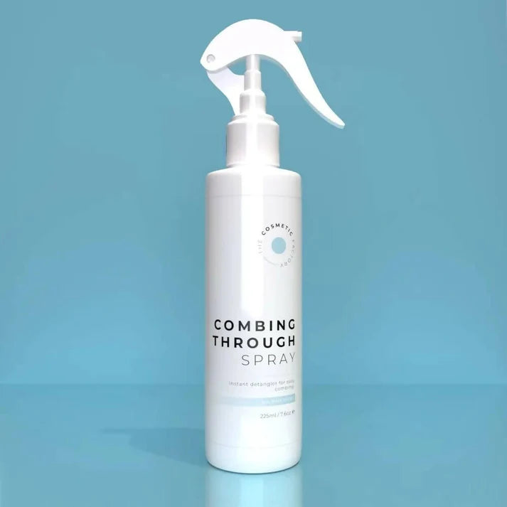 a bottle of combing through spray 225ml against a blue background with mist.