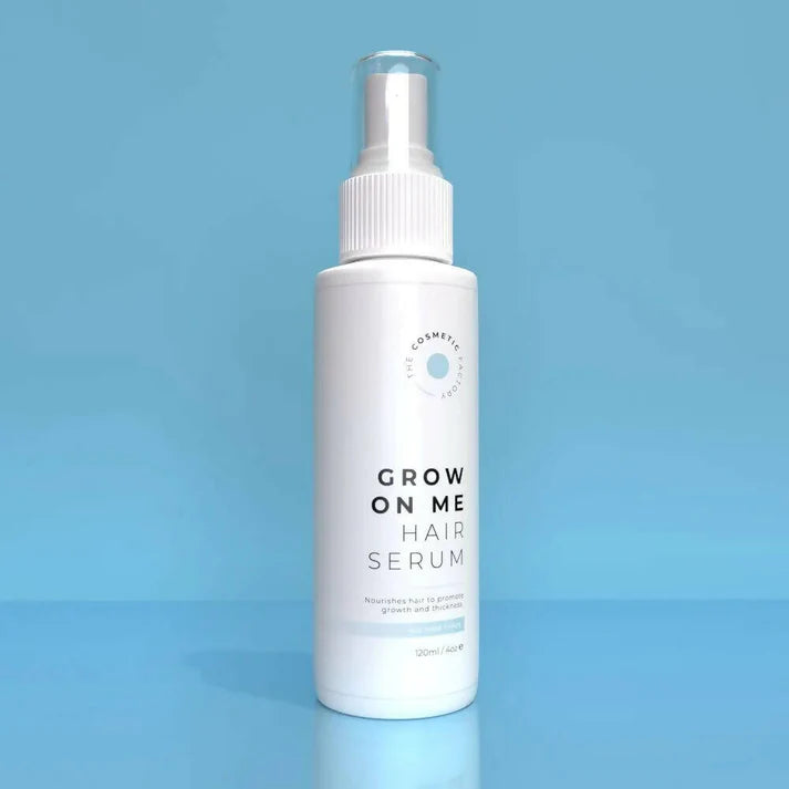a bottle of grow on me hair serum 120ml on a blue surface.