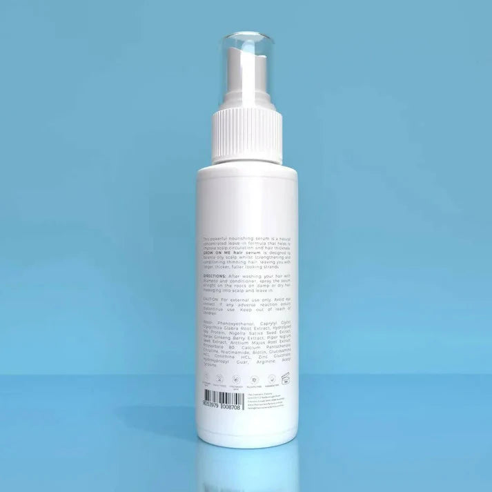 a bottle of grow on me hair serum 120ml on a blue surface.