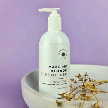 a bottle of make me blonde conditioner 300ml on a purple background with twigs.