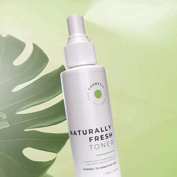 a bottle ofnaturally fresh toner 125ml on a green backgroundwith mistand a green palm leaf.