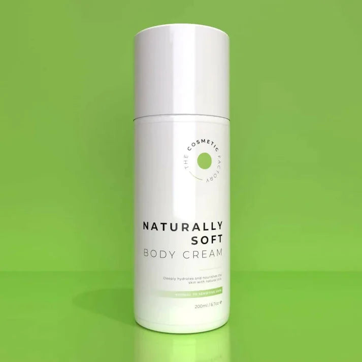 a bottle of naturally soft body cream 200ml on a green surface.