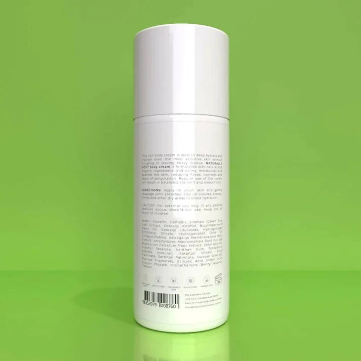 a bottle of naturally soft body cream 200ml on a green surface.