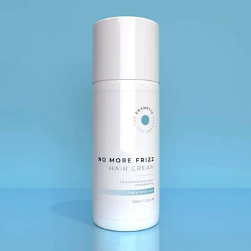 a bottle of no more frizz hair cream 100ml on a blue surface.
